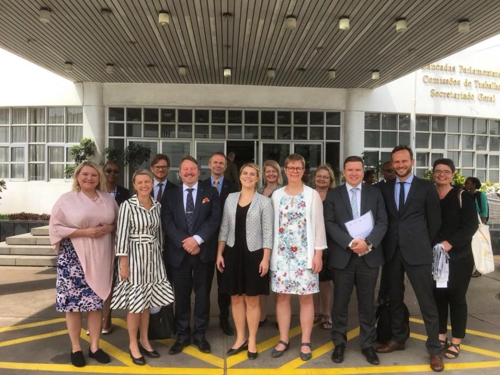 Finnish politicians standing in front of the Parliament of Mozambique.