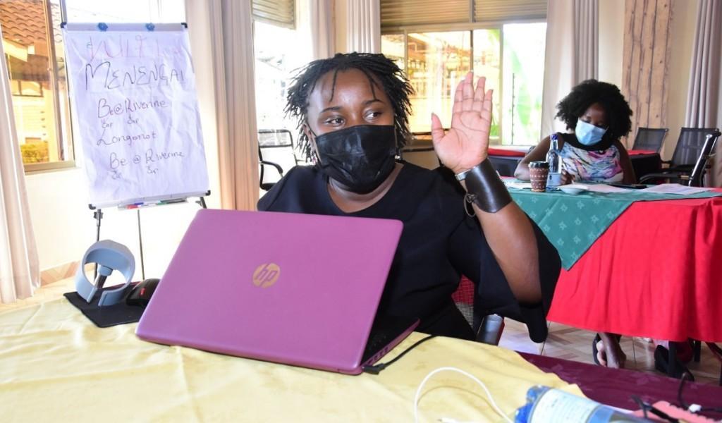 Woman sitting with a laptop and raising her hand