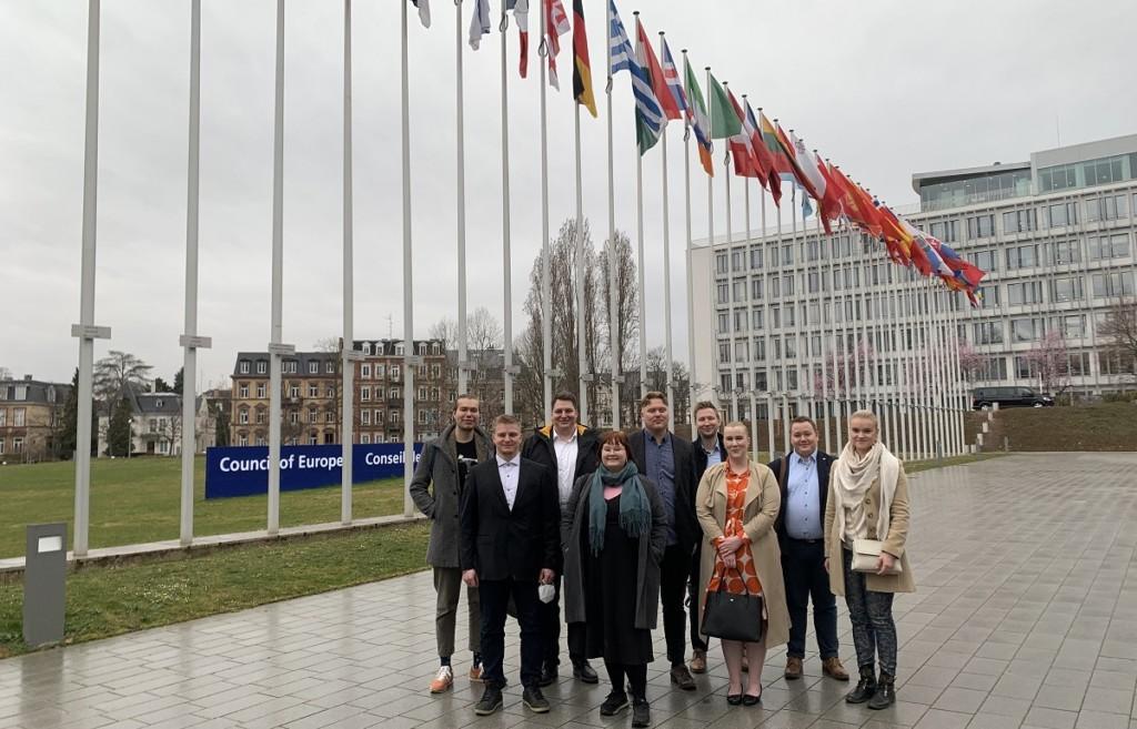 Group of young adults in front of the flags of Council of Europe member states