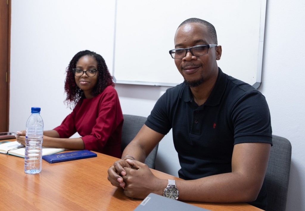 A woman and a man sitting behind a table and looking at the camera