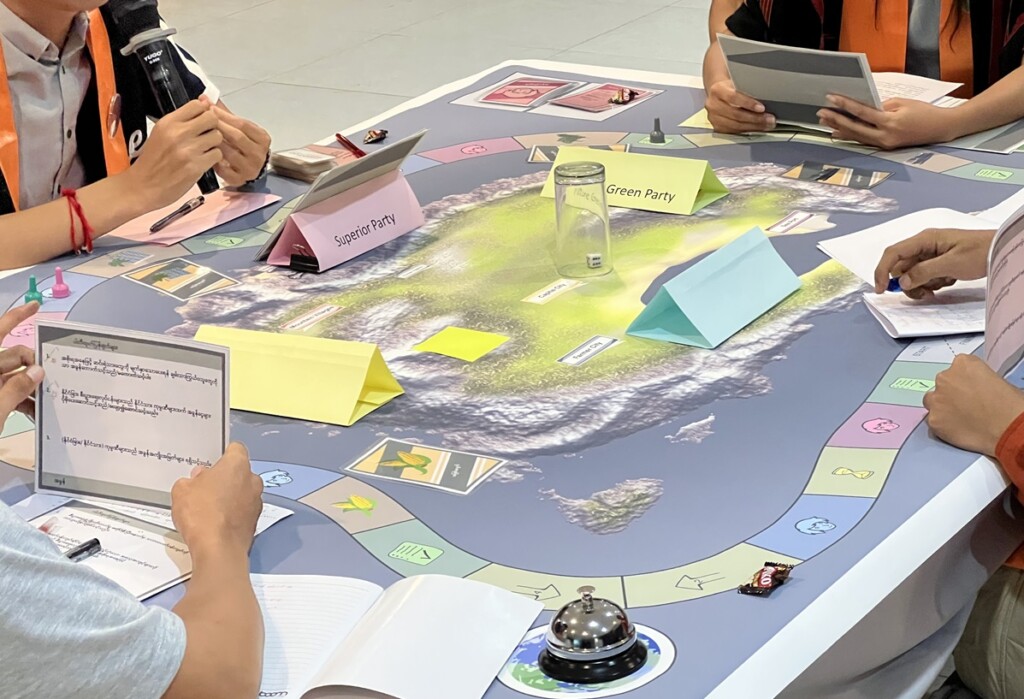 Unidentified people sitting around a table doing exercise that looks like a board game