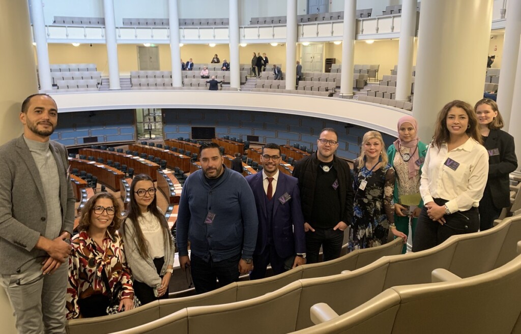 A group of Tunisians standing in front of the plenary hall of the Finnish parliament