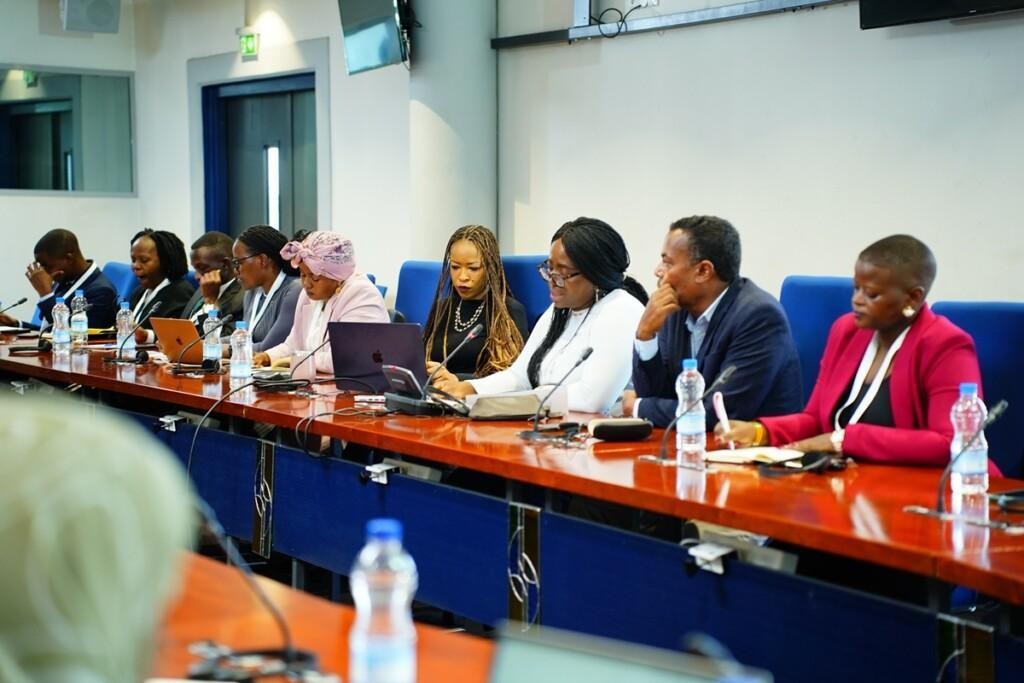 Young people sitting behind a conference table.