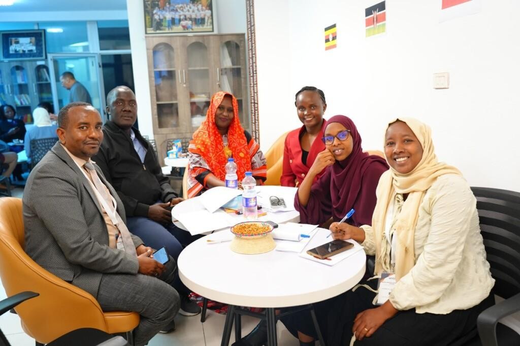 Six people sitting around a table and smiling at the camera.
