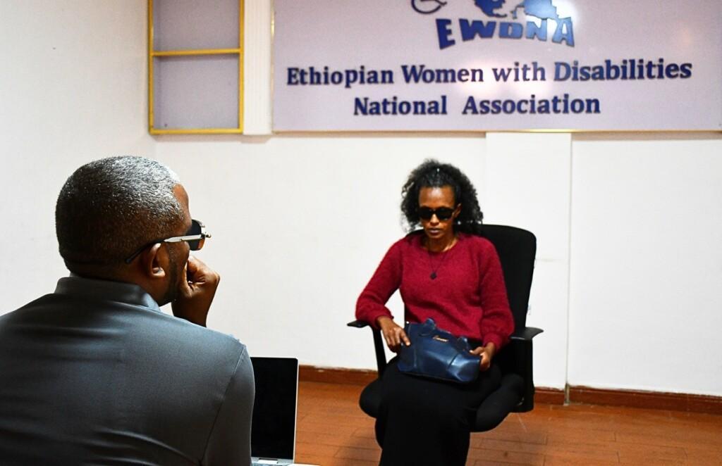A woman wearing dark glasses is being interviewed.